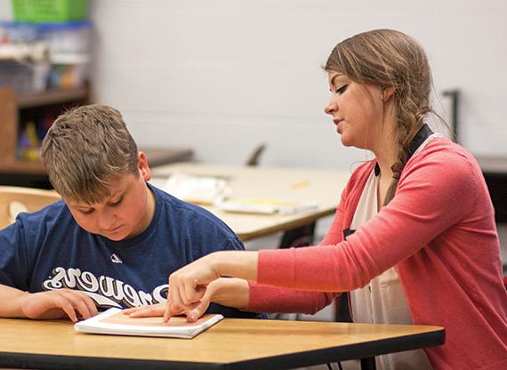 Teacher working closely with a student at a desk